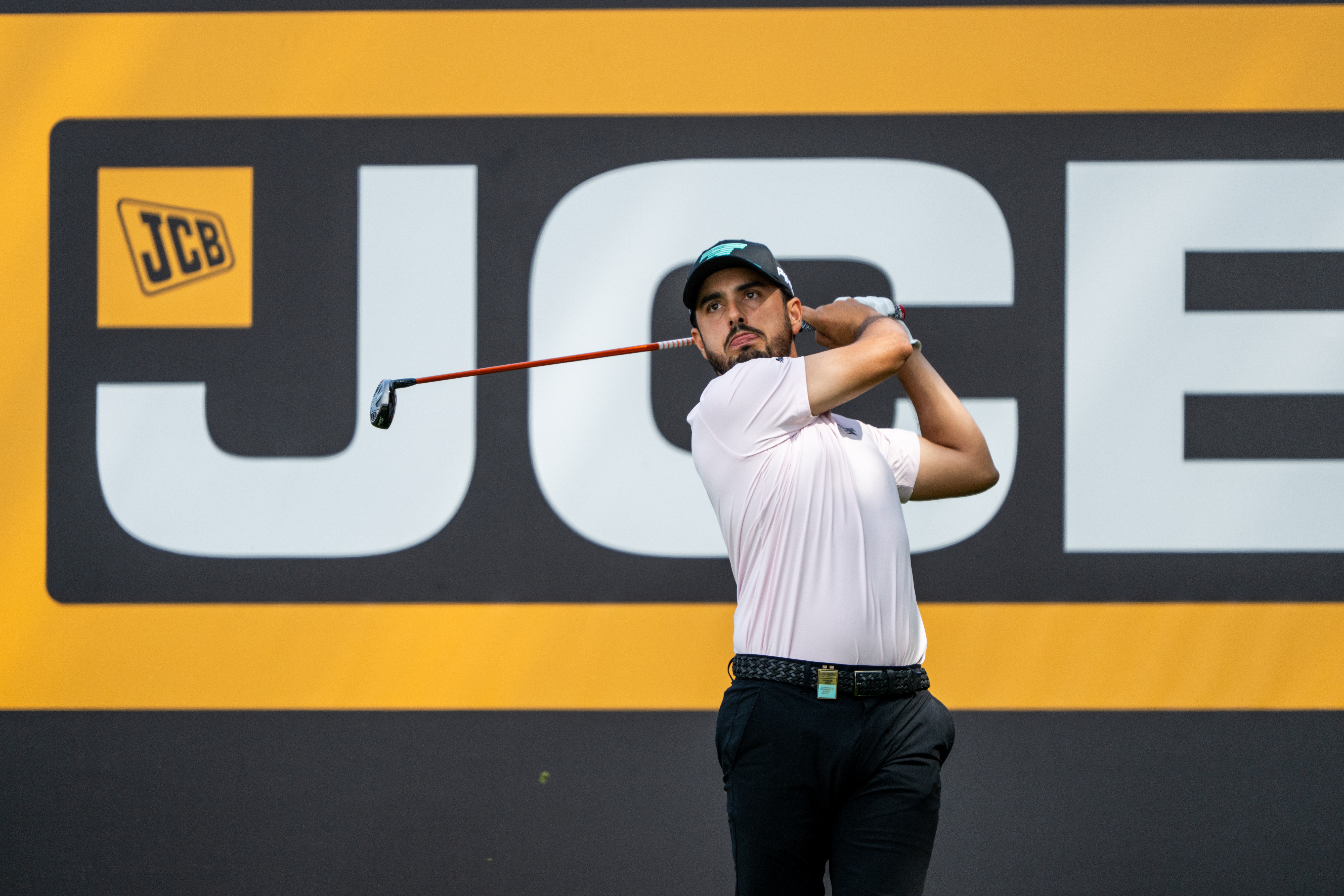 Golfer hits a shot in front of JCB hoarding at LIV Golf UK