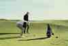 Golfer setting up over the ball on a links fairway with a golf bag