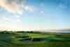 Links hole with pot bunkers and coastline beyond