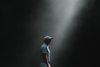 AI-generated atmospheric image of a golfer standing in a shaft of light against a dark background (game-improvement)
