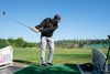 Golfer hitting balls at a practice range to groove a repeatable swing