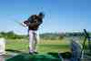 Golfer hitting balls at a practice range net (game-improvement)