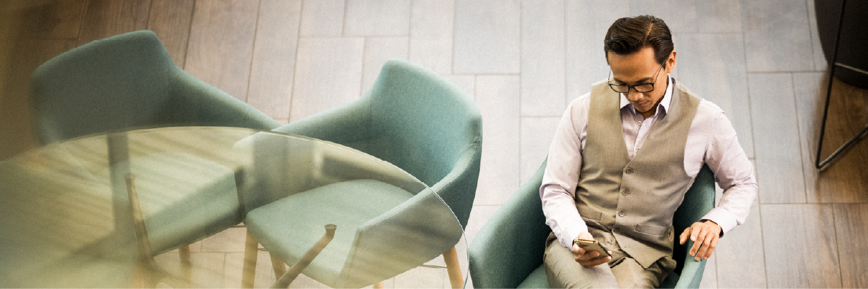 doctor relaxing in a chair in business clothing looking at a phone