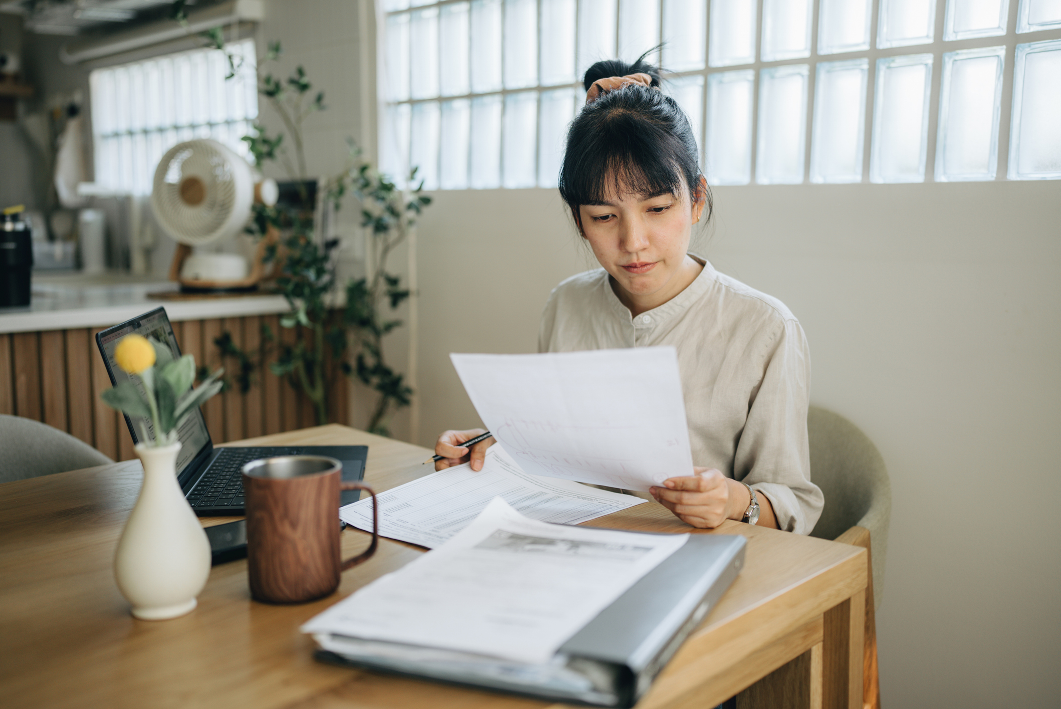 Woman sitting at a kitchen table looking at papework