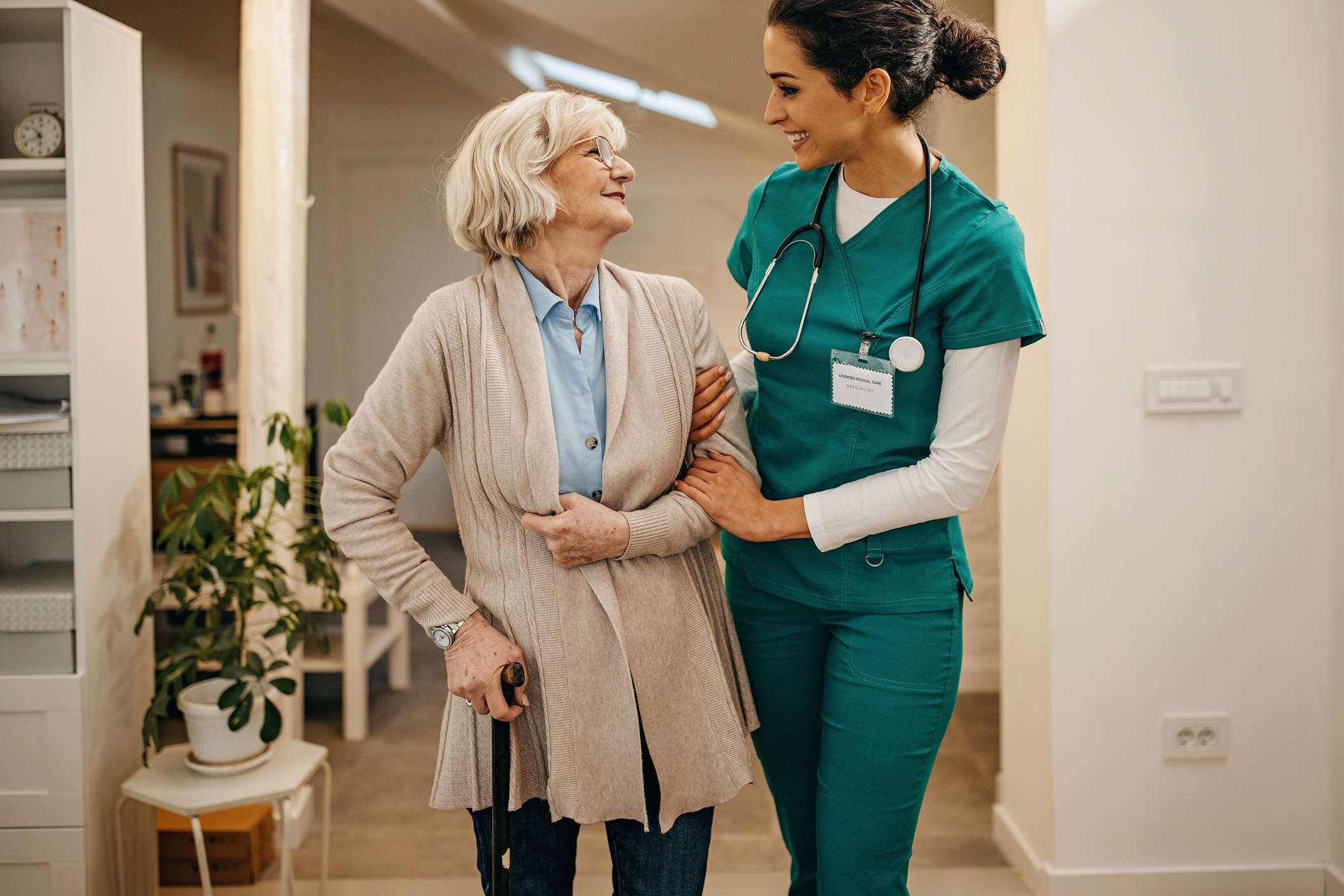 Physician assistant accompanies an older woman through a hallway