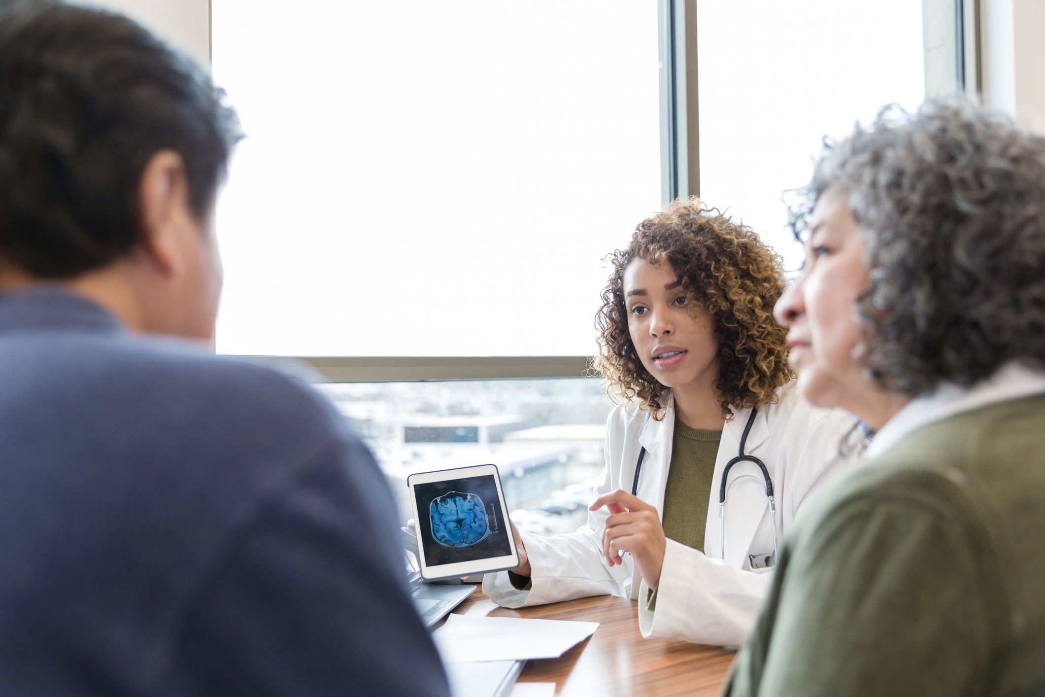 Neurologist discussing an image of a brain with two patients