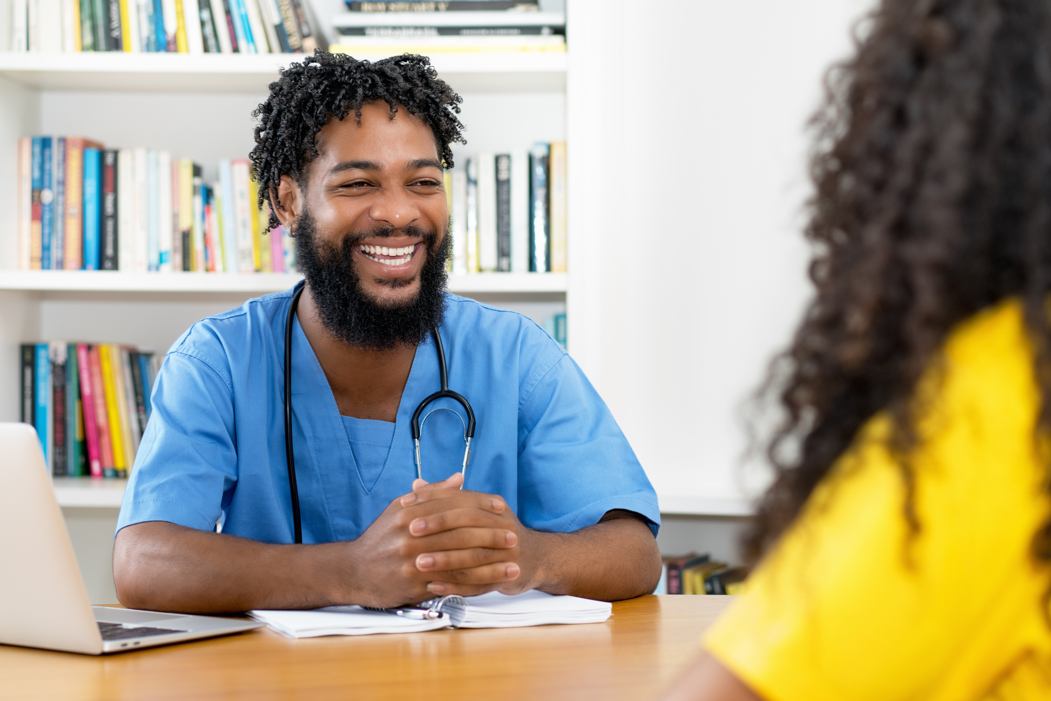 Physician assistant sitting at a desk and talking to a patient