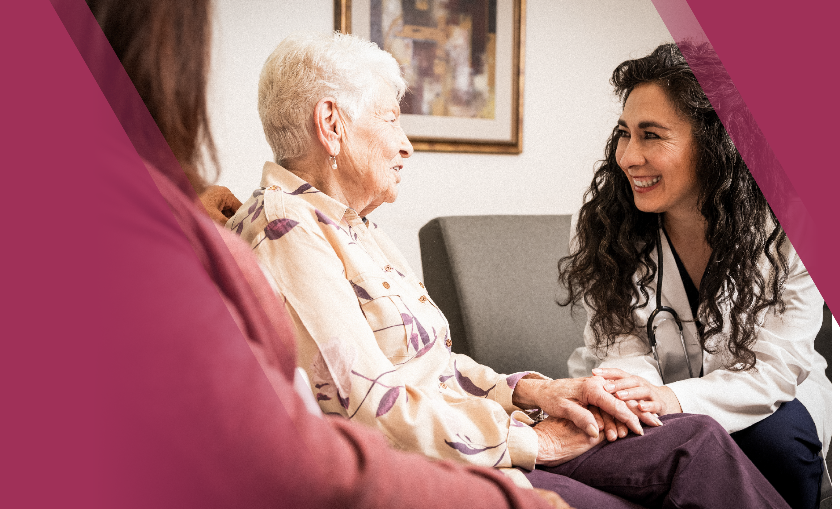 A psychiatrist smiling and holding hands with an elderly woman, sitting on a sofa, engaging in a supportive conversation.