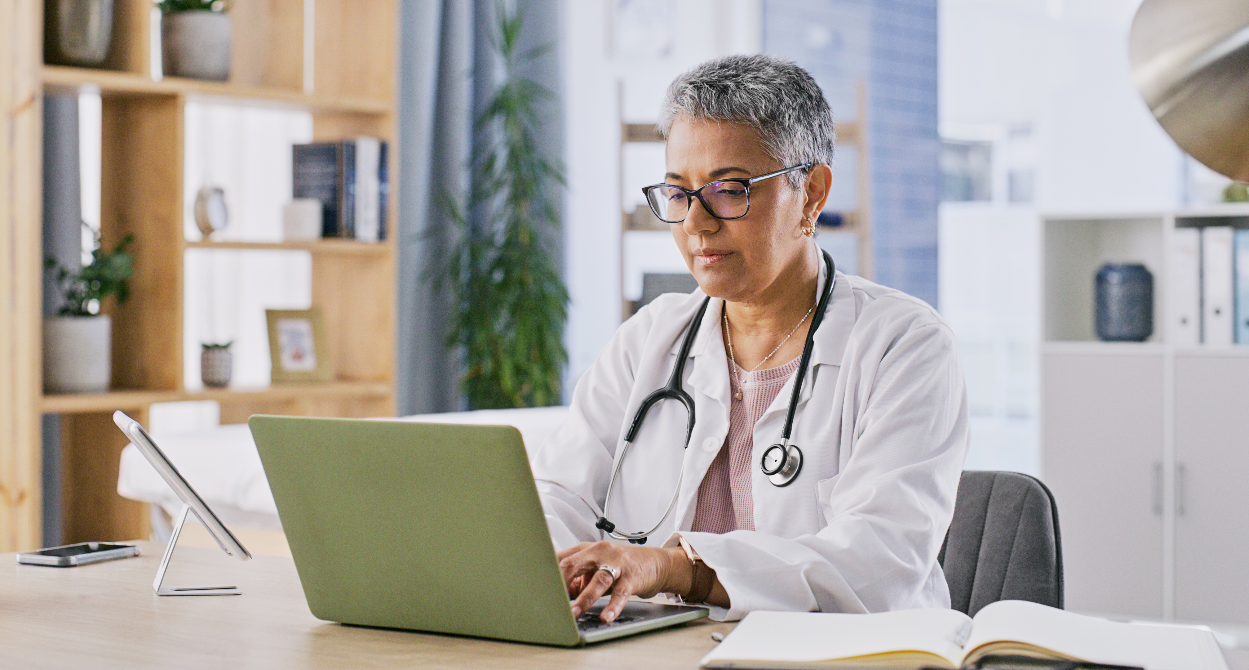Doctor filling out paperwork on laptop