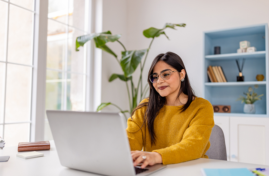 Woman sitting at a desk and looking at a laptop computer at a desk