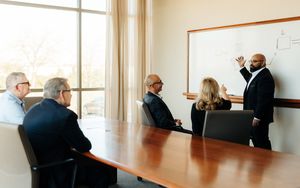 Business man presenting at a whiteboard to four people at a conference table