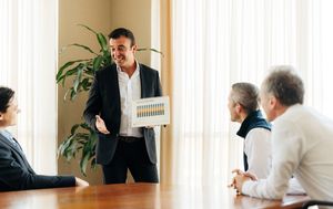 Business man presenting data chart to three others at a conference table
