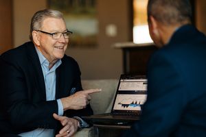 Man presenting financial charts on laptop to another person