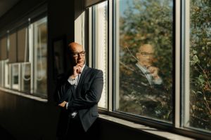Business man in office deep in thought looking out a window