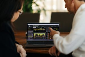 financial charts presented on laptop to another person at a table