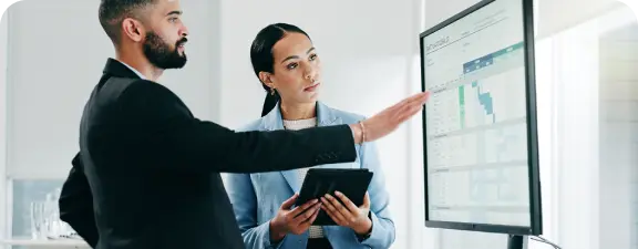 Dos ejecutivos analizan datos en Microsoft Excel, optimizando estrategias y decisiones de negocio.