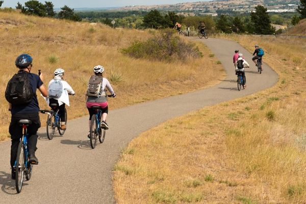 Cyclists ride a paved trail through Montana’s dry hills and open valleys