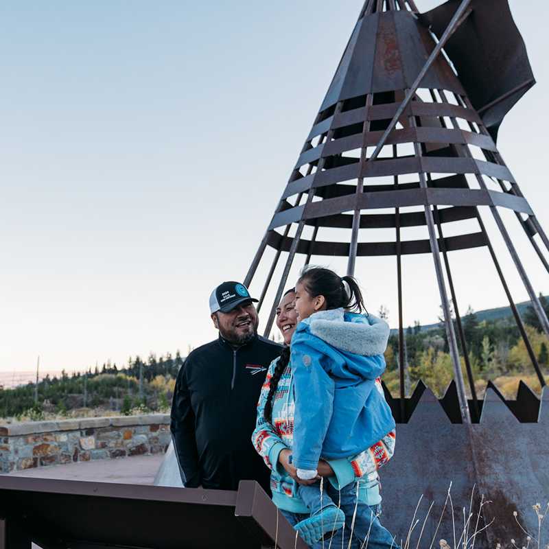 Two people chatting near a stone lookout with a metal tower structure in Montana outdoors