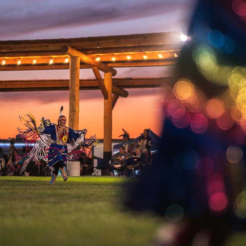 Music performance at an outdoor venue during a Montana sunset with an illuminated crowd and stage lights