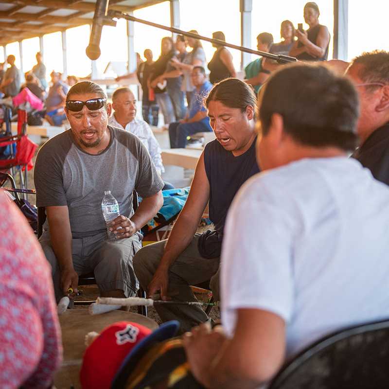 Visitors seated and standing inside a Montana riverboat, watching the guide speak and chatting with others during the tour