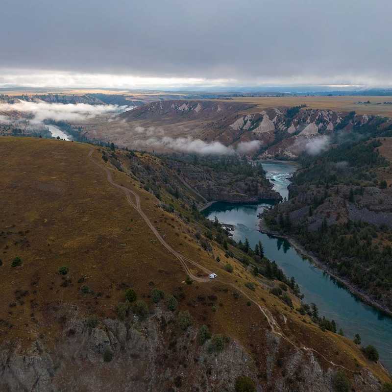 Aerial view of the Yellowstone River winding through Montana canyonland with low clouds over the valley and forested hillsides