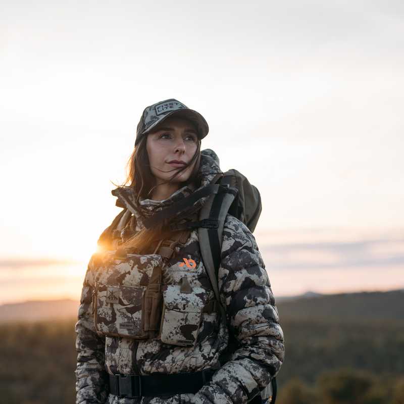 Hiker with a camouflage backpack and trekking poles in the Montana countryside at sunset