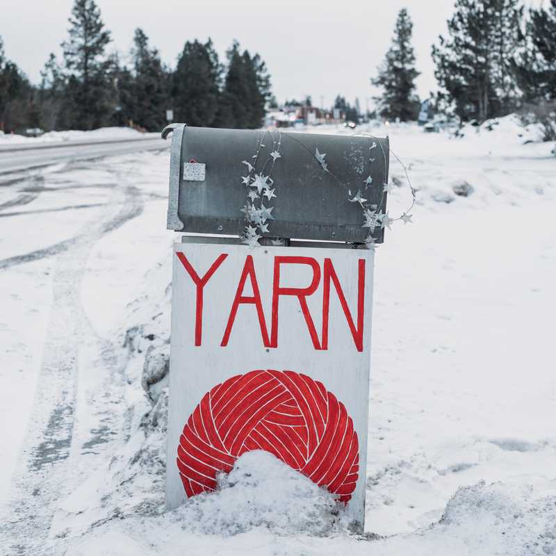 Outdoor trash bin on a snowy Montana roadside with “YARN” written on it