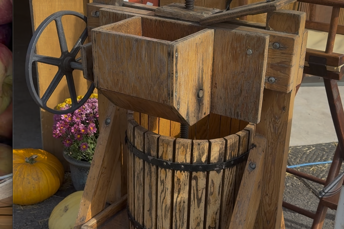 Wood wine press with wooden barrels and hand crank outdoors on a porch in Montana