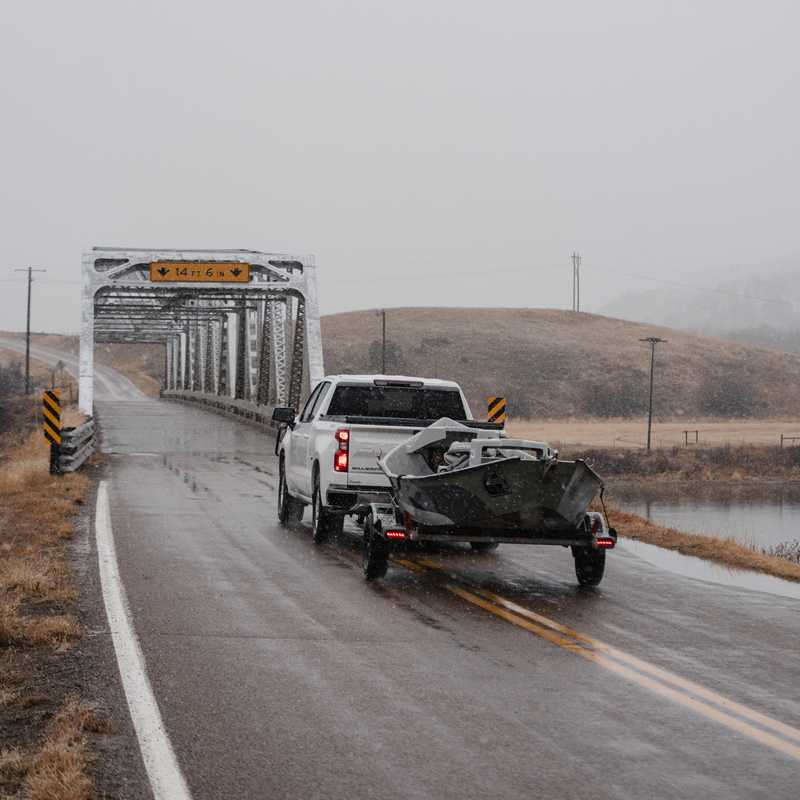 Trucks traveling on a rural Montana highway in fog near open fields and low hills