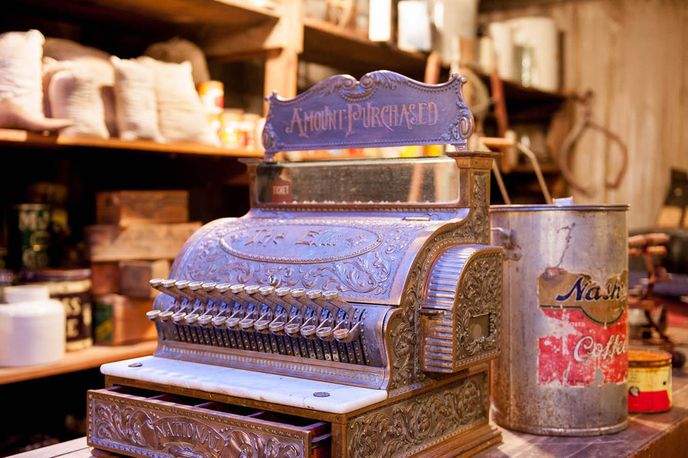 Antique store display with a vintage cash register and branded tin canisters on a shelf, Montana marketplace setting
