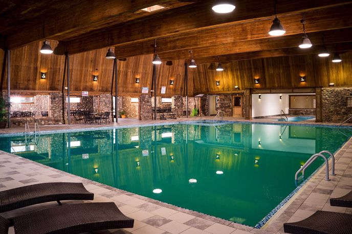 Indoor swimming pool with hot tub seating in a wood-paneled Montana lodge
