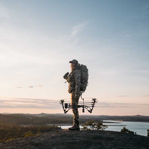 Hiker with a drone backpack standing on a bluff above a Montana landscape at sunset