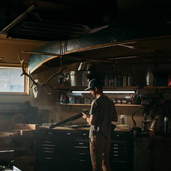Person standing at a bar in a rustic Montana workshop with shelves and equipment behind them