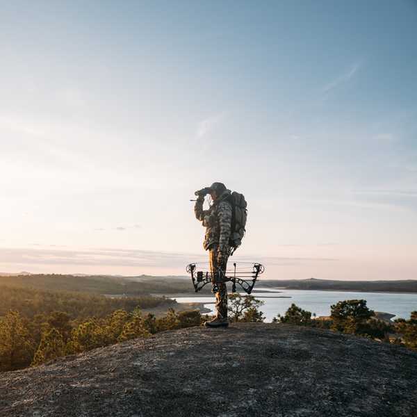 Backpacker with a large pack standing on a rocky overlook above a lake at sunrise in Montana