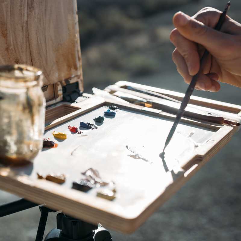 Person assembling a wooden outdoor project, using metal tools and small parts on a tabletop outdoors in Montana