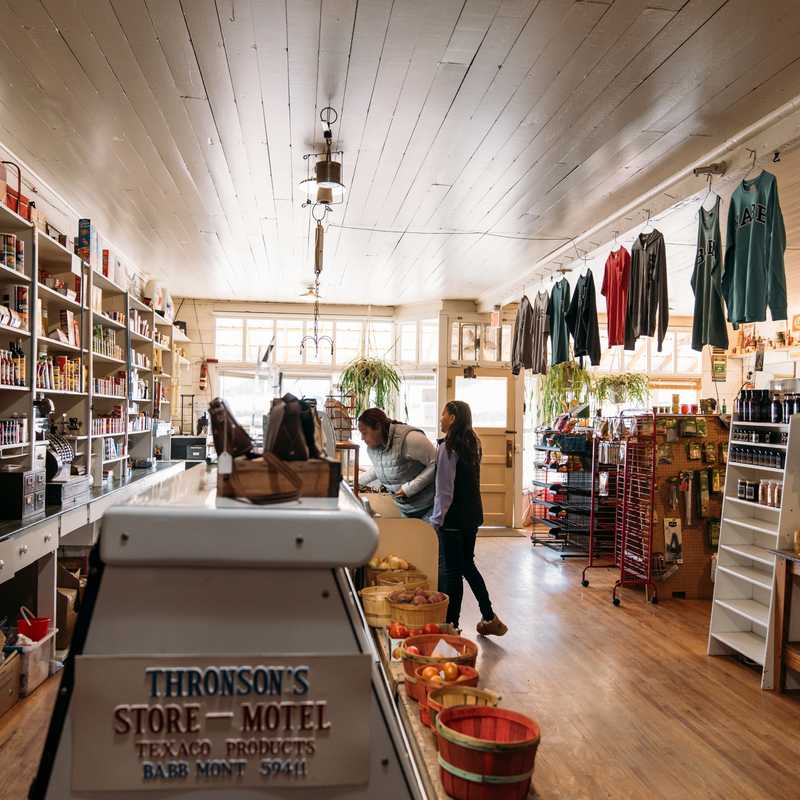 Interior of a Montana store with shelves of goods and visitors shopping near the register area