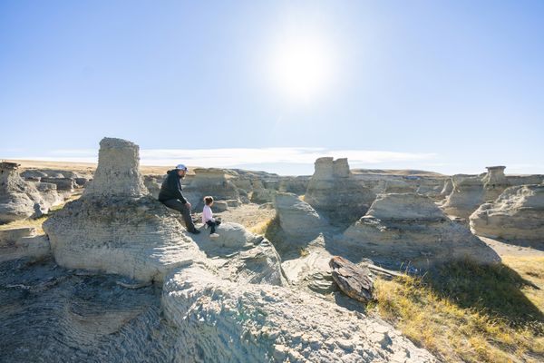 Person sitting on a rocky overlook at Theodore Roosevelt National Park overlooking the badlands landscape