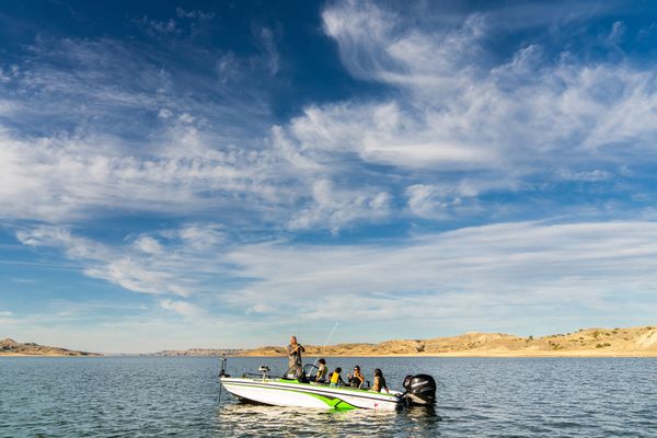 People riding in a boat on a Montana lake with distant hills and a blue sky