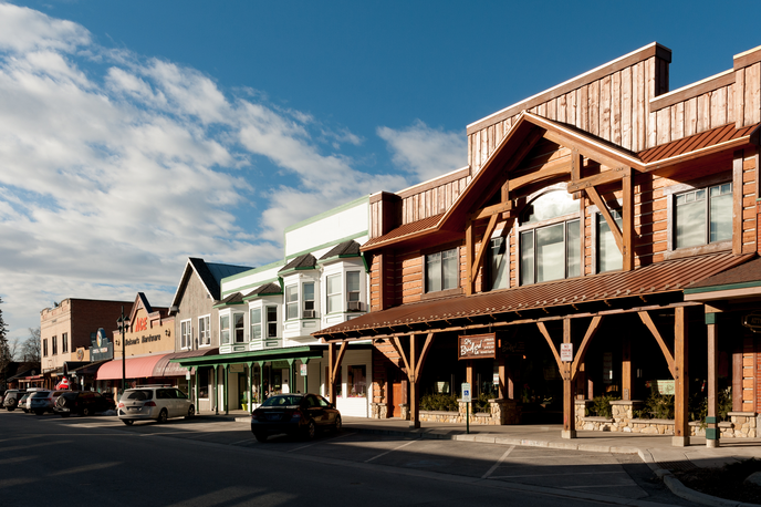 Downtown storefront buildings along a Montana main street with wooden architecture and storefront signs under a blue sky