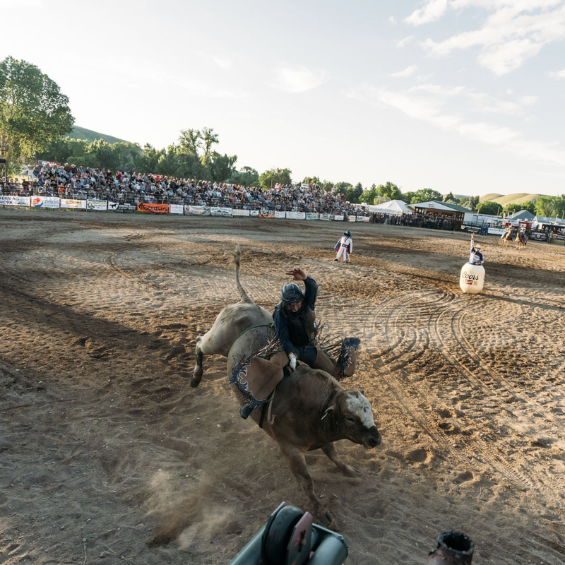 Riders on horses in a dusty outdoor arena during a competitive event in Montana
