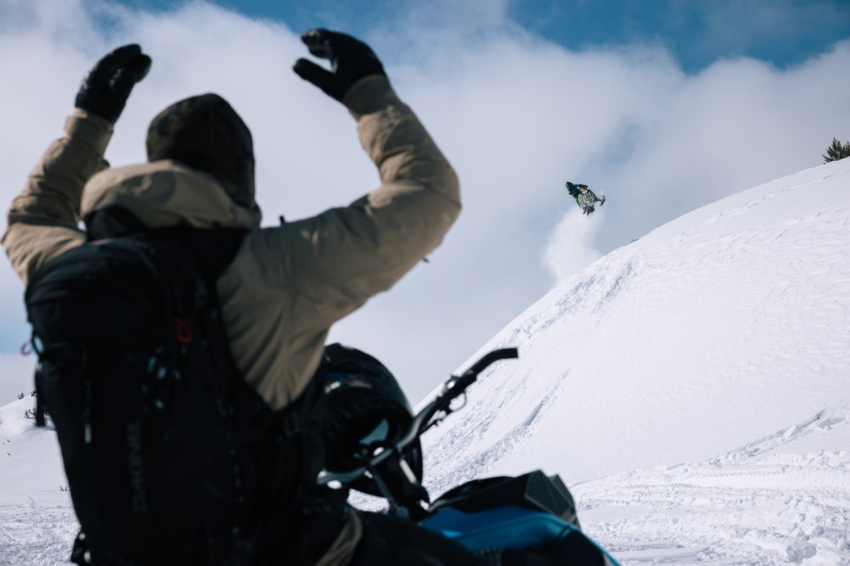 Skiers on a snowy Montana slope with lift chair and clouds in the background