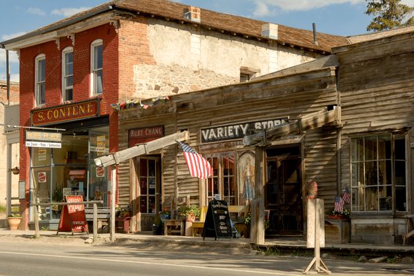 Historic storefronts along a Montana main street, including a variety store with an American flag displayed outside
