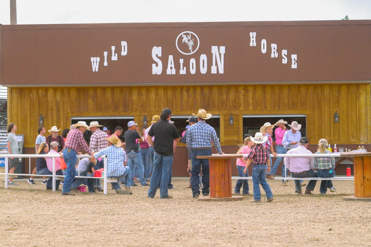 People gather at the Wild Horse Saloon in Montana, with a live country western band visible through the open entrance.