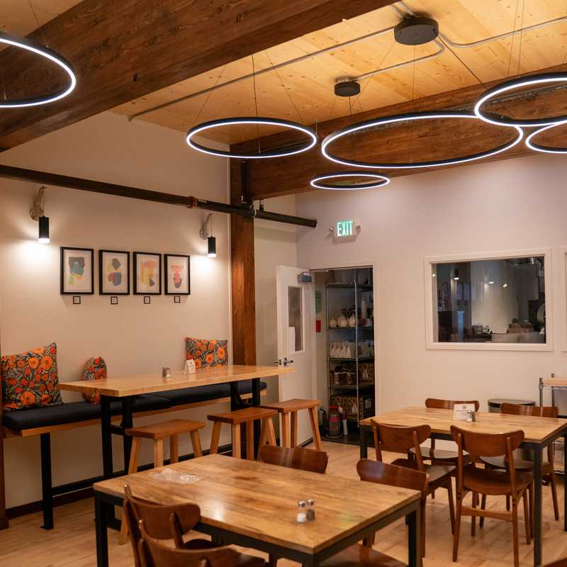 Cozy dining area inside a Montana lodge with wooden tables and chairs, bar counter, and ambient oval ceiling lights