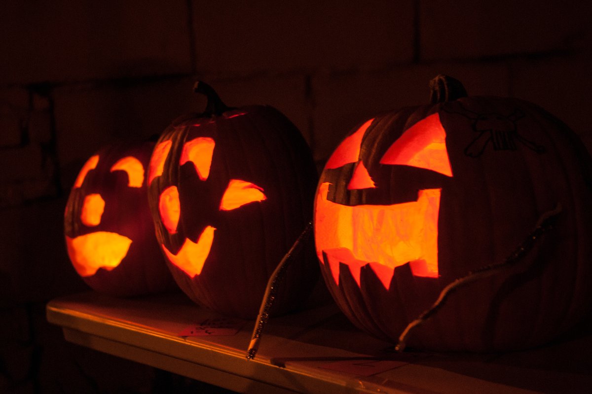Carved jack-o’-lanterns glowing on a table at night