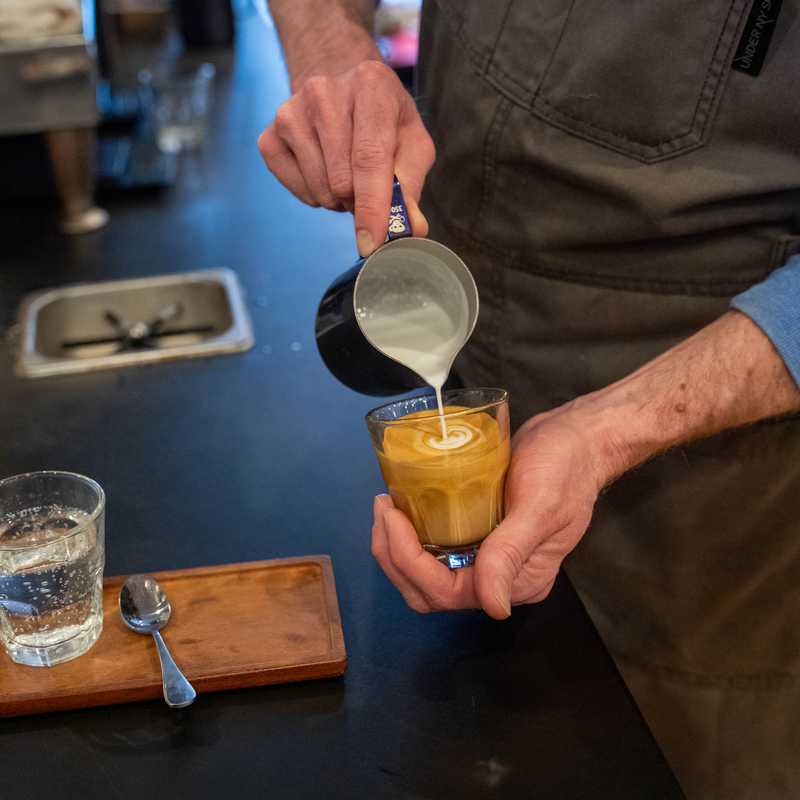 Bartender pours a drink from a shaker into a low glass at a bar counter