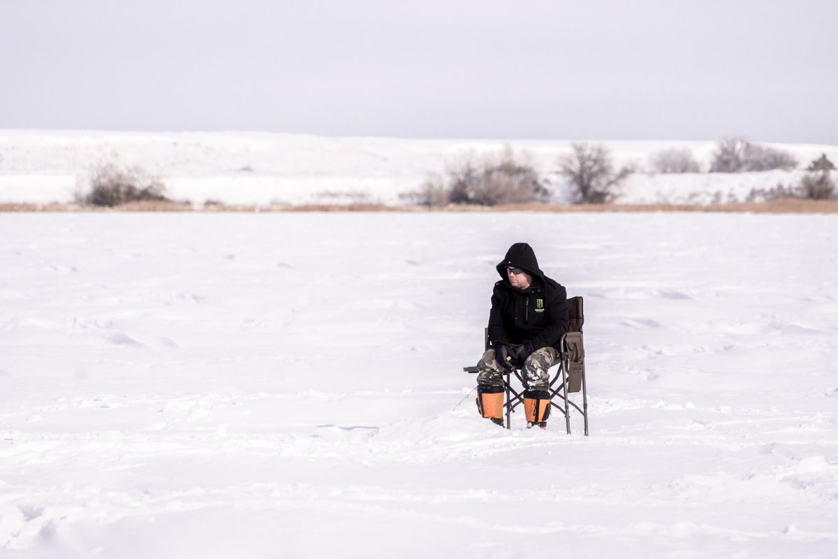 Person riding a horse-drawn sleigh across a snow-covered field in winter landscape near Montana