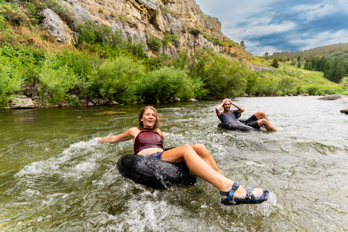 People floating down a river through Montana hills and cliffs on inner tubes