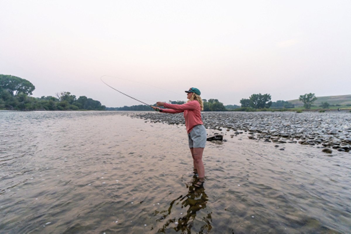 Angler casting a line from the shoreline on a Montana lake at dusk