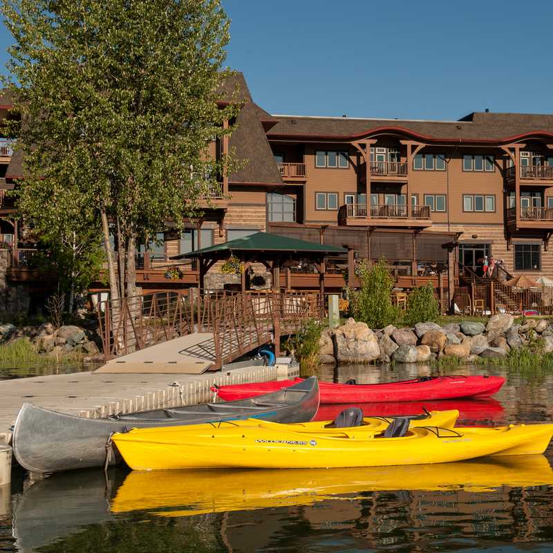 Kayaks tied along a riverbank in front of a riverside lodging building in Montana